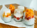 Pyszny deser chia z mango i truskawkami w szklankach, ułożony warstwowo z jogurtem i płatkami owsianymi.
