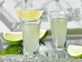 Dwa kieliszki z drinkiem Kamikadze, ozdobione solą i plasterkami limonki. Idealny przepis na orzeźwiający shot.