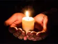 Hände umschließen eine Kerze, die ein warmes Licht spendet. Ein Symbol für evangelische Gebete und Hoffnung in der Dunkelheit.