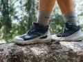 Buty trekkingowe Salomon na pniu drzewa w lesie. Salomon to firma znana z wysokiej jakości obuwia outdoorowego.
