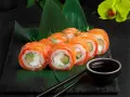 Roladki sushi z łososiem i awokado, podane na liściach. Inspiracja, jak zrobić sushi.