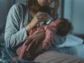 Mama karmi butelką niemowlę, które obudziło się w nocy z płaczem.