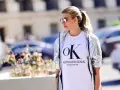 Kobieta w srebrnej kurtce CK damskiej i białej koszulce z logo Calvin Klein Jeans.