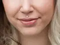 Delikatny labret co to? To ozdoba wargi w kształcie kwiatka z cyrkoniami. Obok kolczyk w nosie.