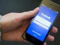 Eine Hand hält ein Smartphone mit der Facebook-Anmeldeseite.