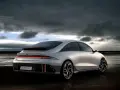 Srebrny Hyundai Ioniq 6 na plaży pod pochmurnym niebem.