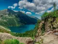 Majestatyczne tatry szczyty otaczają turkusowe Morskie Oko. Chmury na niebie dodają dramatyzmu krajobrazowi.