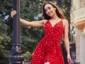 Junge Frau in einem roten Kleid mit Polka Dot Muster lehnt an einer Laterne.