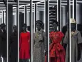 Manichini con abiti eleganti, un omaggio all'eleganza e all'origine Dior. Rossi, neri e grigi, con cappelli e sciarpe.