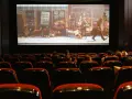 Una sala de cine con público observando una película animada. Esto es que es el cine: una experiencia compartida de historias en pantalla grande.
