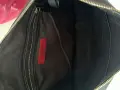 Wnętrze czarnej torebki Valentino z widoczną czerwoną metką marki. Złoty zamek błyskawiczny i kilka przegródek.