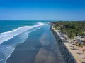 Słoneczne plaże Gambii z palmami i turkusowym oceanem. Ludzie spacerują wzdłuż wybrzeża, ciesząc się pięknem natury.