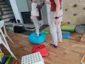 Dziecko ćwiczy równowagę na niebieskiej poduszce, część domowej ścieżki sensorycznej dla dzieci.