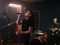 Wokalistka z pasją śpiewa w zespole, podczas gdy gitarzysta i perkusista tworzą rytm w studiu nagraniowym.