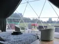 Wygodne łóżko i fotele w kopule z widokiem na zielone ranczo targówka.