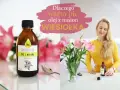 Butelka oleju z wiesiołka obok kobiety w żółtej bluzce i bukietu różowych lilii. Napis: "Dlaczego warto pić olej z nasion WIESIOŁKA".