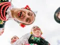 Uśmiechnięci młodzi ludzie w barwnych strojach ludowych, żywa ludowa twórczość artystyczna.