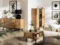 Drewniane meble i subtelne dodatki tworzą przytulną atmosferę w stylu hygge. Wazon z gałązkami i czarna lampa dodają elegancji.
