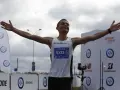 Dariusz Nożyński triumfalnie kończy bieg, z ramionami uniesionymi ku niebu.