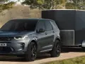 Szary Land Rover Discovery Sport z przyczepą o masie 2000 kg jedzie po leśnej drodze.