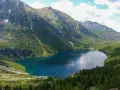 Górskie jezioro Morskie Oko otoczone zielonymi lasami i skalistymi szczytami.