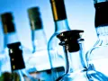 Kilka szklanych butelek alkoholu na niebieskim tle.