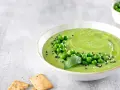 Cremoso hummus di piselli guarnito con piselli freschi, basilico e semi di sesamo, servito con cracker croccanti.