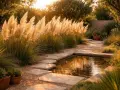 Goldene Abendsonne beleuchtet Pampasgras am Teichrand. Ein Steinpfad führt durch den Garten, der einen perfekten Pampasgras Standort zeigt.