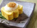 Delikatny omlet tamago, zwinięty w rolki, podany z tartą rzodkwią i grzybami enoki na talerzu z bambusowym wzorem.