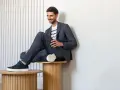 Uśmiechnięty mężczyzna w granatowym garniturze i białej koszulce w paski, idealny przykład dress code smart casual.