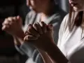 Two women pray, hands clasped. One's face is blurred, the other's lips are visible. This scene evokes the devotion of a deaconess in the bible.