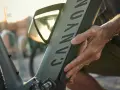 En hand justerar en elcykel. Solen skiner genom ett fönster på cykelns ram.