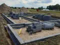 Budowa fundamentów z bloczków betonowych. Zastanawiasz się, ile kosztuje wylanie fundamentu? Na placu budowy widać materiały i postęp prac.