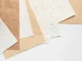 Różne rodzaje papieru, od jasnych po brązowe, z widoczną fakturą i złotymi drobinkami. Różna grubość papieru.