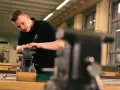 Ein junger Mann macht ein Praktikum und arbeitet konzentriert an einem Schraubstock in einer Werkstatt.