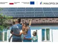 Rodzina podziwia panele słoneczne na dachu, symbolizujące walkę ze stratami ciepła w budynku i dążenie do niezależności energetycznej.