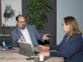 Ein Anwalt für Krankenversicherungsrecht erklärt einer Mandantin am Tisch komplexe Sachverhalte.