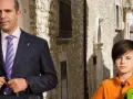 Checco Zalone con uno dei suoi figli, un bambino con un pallone da calcio, passeggiano in un vicolo.