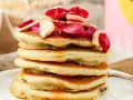 Stapel fluffiger Pfannkuchen mit gefriergetrockneten Erdbeeren und Bananen, perfekt für gesunde Snacks selber machen.