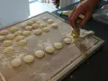 Ręcznie robione ciasto na ravioli, wycinane okrągłym wykrawaczem. Widać wiele gotowych krążków na desce.