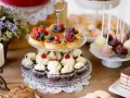 Stół z ciastkami, babeczkami, tartaletkami z owocami i cake pops.