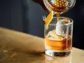 Idealny wieczór: nalewanie whisky z colą do szklanki z lodem i skórką pomarańczy.