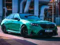Błyszczące, zielone BMW M5 G90 z czarnymi felgami stoi na tle przemysłowych rur.