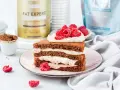 Pyszny keto tort urodzinowy z kremem i malinami, obok proszek tłuszczowy i słodzik.