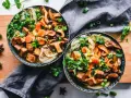 Dwie miski aromatycznego bulionu z makaronem, grzybami, marchewką i kostkami pysznego tofu na kolację.