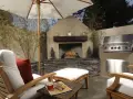 Un patio privado con chimenea, parrilla y cómodos asientos bajo sombrilla. Ideal para techar patio comunitario de uso privativo.