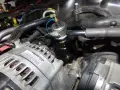 Close-up of a p0520 Dodge engine bay, showing the alternator and a fuel pressure regulator.