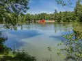 Idyllischer sulzfeld badesee mit Spielplatz und Rutsche, umgeben von grünen Bäumen.