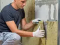 Operaio con guanti installa isolante in lana di roccia. Il depron è muffa, ma questo materiale isolante previene la sua formazione.