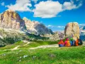 Quattro escursionisti ammirano le maestose Dolomiti Trentino Alto Adige, con cime imponenti e un cielo azzurro.